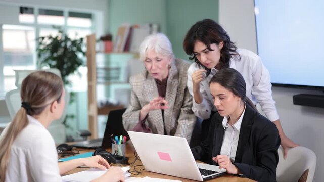 Group of women gathered around sitting colleague, and look at monitor screen, discuss work tasks. Travel agency, business regional representative office of international company, engineering company