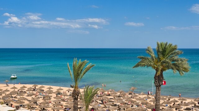 Hammamet, Tunisia - MAY 16, 2025: Beach of Hammamet, the first tourist destination in Tunisia. Located on the Gulf of Hammamet. Beach and boats on shallow water, view on Mediterranean sea. Crystal-cle