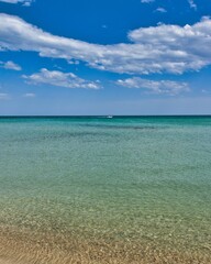 Fototapeta premium Hammamet, Tunisia - MAY 16, 2025: Beach of Hammamet, the first tourist destination in Tunisia. Located on the Gulf of Hammamet. Beach and boats on shallow water, view on Mediterranean sea. Crystal-cle