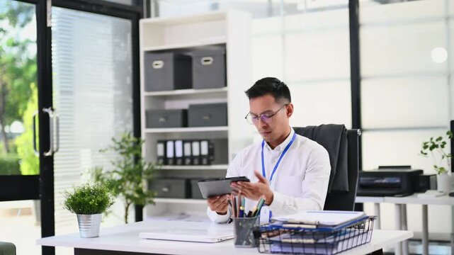 Asian businessman packing personal belongings into a cardboard box, clearing his office desk after resignation