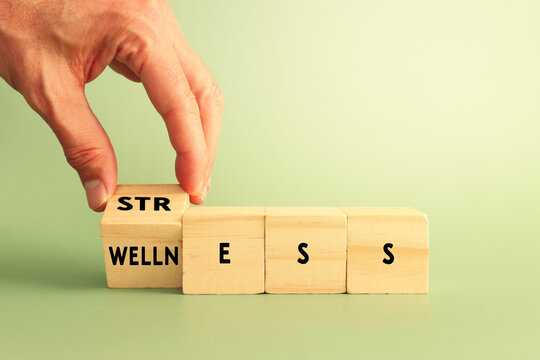 Hand flipping wooden cubes to replace the word stress with wellness