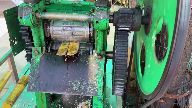 traditional sugarcane juice extraction machine crushing fresh cane at local street stall