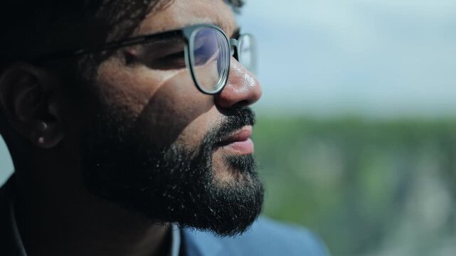 Close-up profile of serious male executive in glasses watching city view through window. Concept of deep thinking, visionary leadership, strategic planning professional mindset in corporate workspace.