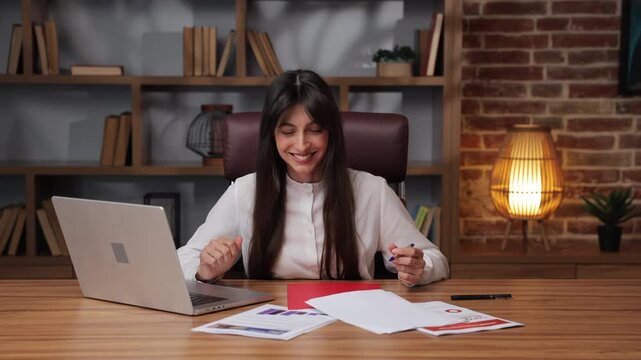 Business woman shows excitement and joy while working at her desk.
