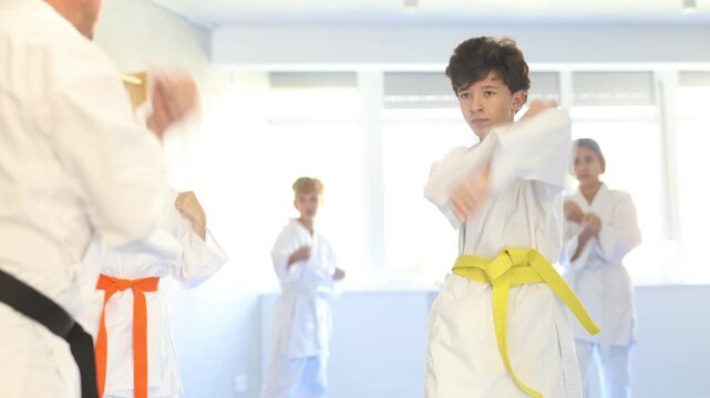 Children athletes starting position and studying and repeating sequence of punches and painful techniques in karate kata technique. Oriental martial arts, training and obtaining black belt