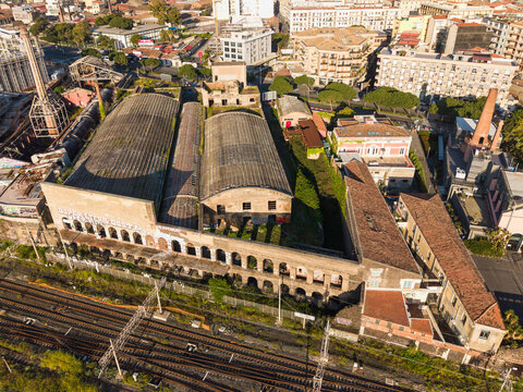 Aerial view of the historic industrial complex with vaulted roofs and brick arches next to railway tracks in Catania, Sicily, Italy.