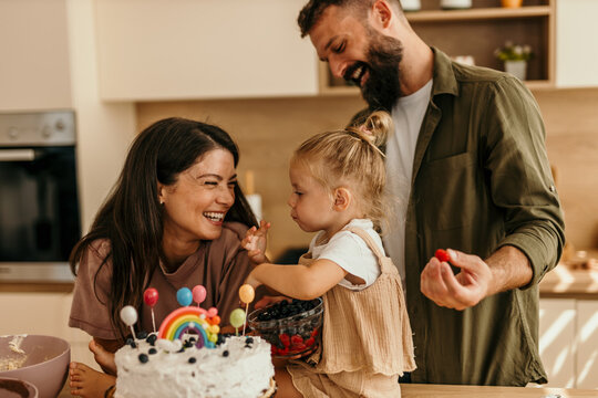 Family celebrating child's birthday baking cake together