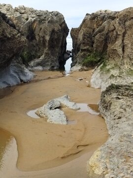 Pasadizo natural entre grandes rocas en una playa de Cantabria