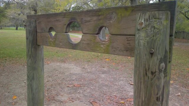 Gimbal close-up panning shot of a recreated 17th century wooden pillory at Old Charles Towne Landing in South Carolina. 4K