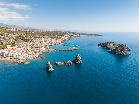 Aerial view of the Islands of the Cyclops rock formations in the turquoise Mediterranean sea along the coast of Aci Castello, Catania, Italy.