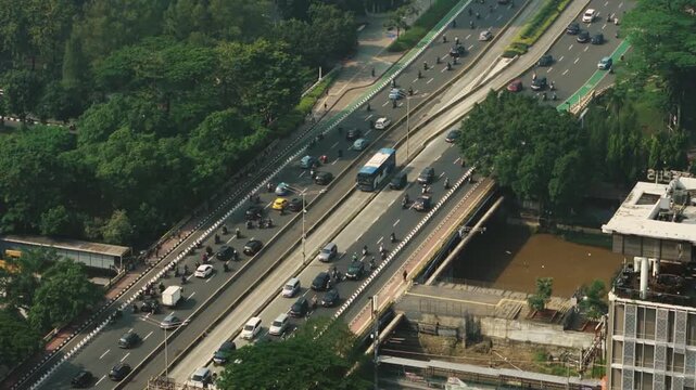 Drone perspective flying above an urban multi tier highway interchange surrounded by trees