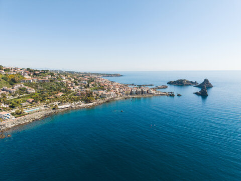 Aerial view of the Islands of the Cyclops and the coastal town of Aci Castello with volcanic rocks and blue sea Aci Castello, Italy.
