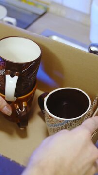 Packing mugs and cups into box for moving out