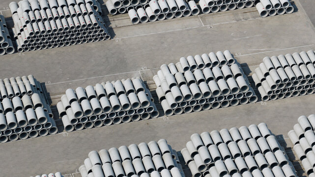 Aerial view of neatly stacked concrete pipes in an industrial storage yard with rows of cylindrical tubes on a paved surface Oosterhout, North Brabant, Netherlands.