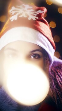Christmas cute woman with Santa hat looking at the camera surrounded with lights