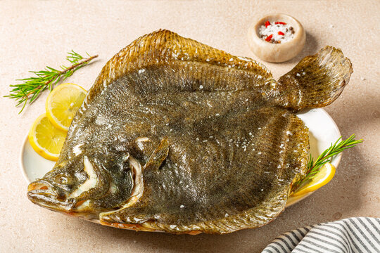 Close iup of Cooked, oven baked  Whole Turbot fish in a plate, with lemon and rosemary.