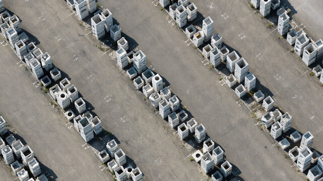 Aerial view of rows of precast concrete blocks and industrial components stored in an asphalt yard with numbered sections in Oosterhout, North Brabant, Netherlands.