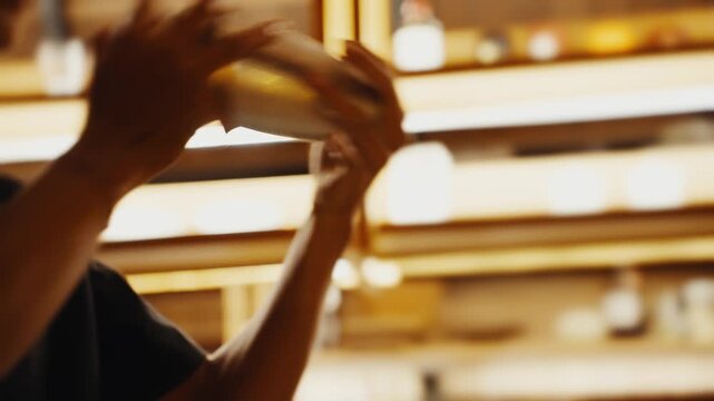 Bartender hands shaking cocktail shaker at bar
