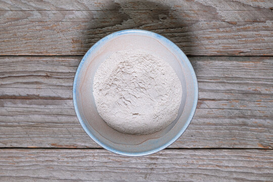 Whole Grain Buckwheat Flour in Handmade Ceramic Bowl on Weathered Wood