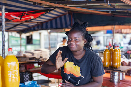 Smiling African woman selling homemade juice and grains at a market stall
