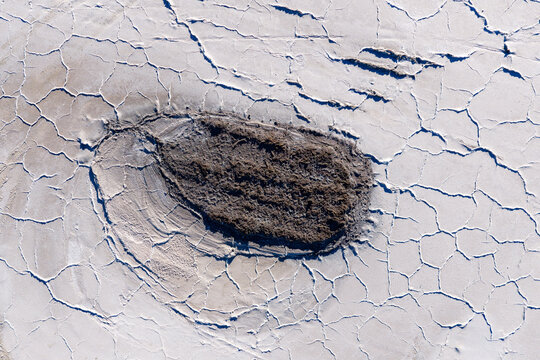 Aerial view of the Uyuni Salt Flat featuring a dark mud pool surrounded by intricate cracked salt crust patterns Potosi Department, Bolivia.