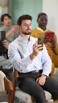 Man in shirt take photo of presentation slide or scan code. Collection of information and data on latest changes in tax legislation, trends in public speaking, innovations in programming