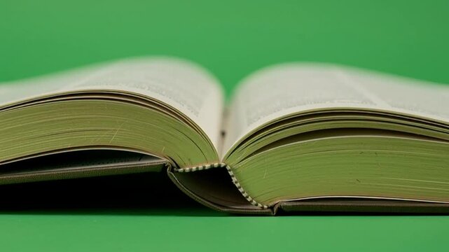 Open Book Pages Turning on a Solid Green Background.