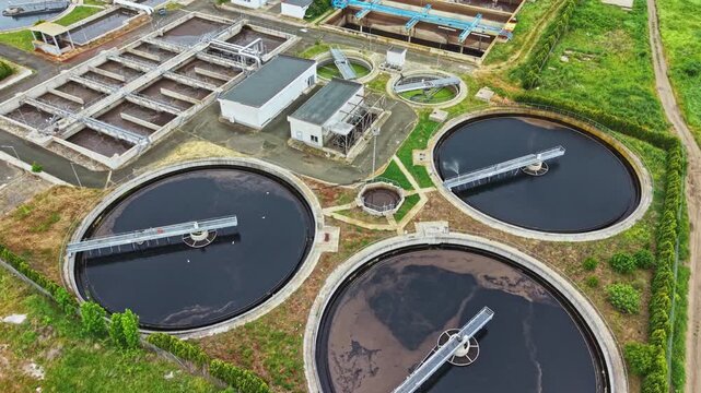 Aerial treatment basins captured with drone showing triple circular clarifiers, nearby rectangular settling tanks, access walkways, and maintenance platforms