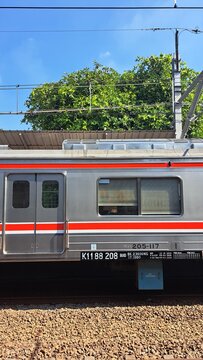 Side View of KRL Commuter Line Electric Train Carriage at a Station in Jakarta, Indonesia on a Clear Day