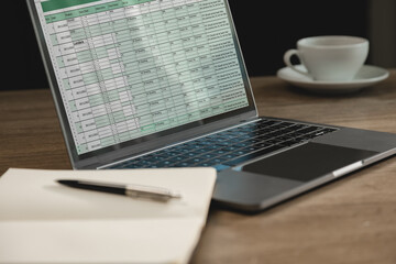 Laptop displaying spreadsheet dashboard with business data and project tracking table on workspace...
