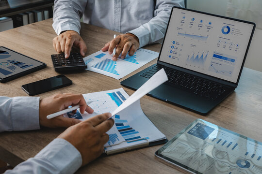 Business team reviewing accounting financial reports with calculator, charts, tablet, and dashboard on laptop during office meeting, supporting budget analysis, financial planning, and reporting workf