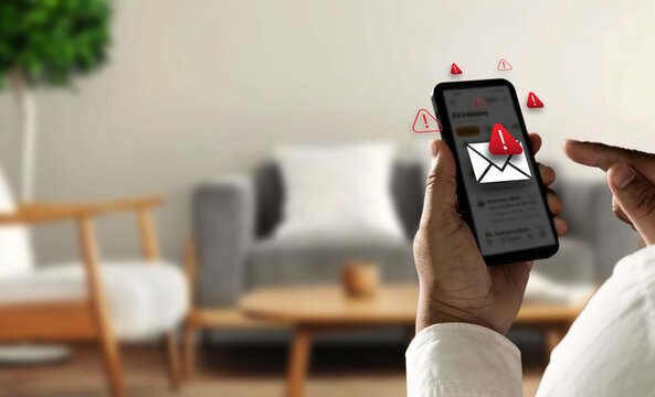 Person holding smartphone with spam warning icons and fake message alert interface, representing SMS phishing attack, mobile scam risk, online fraud prevention, and cyber security protection.
