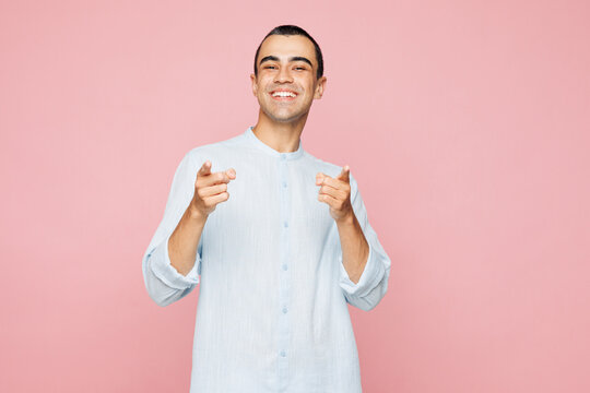 Young middle eastern man he wears casual blue cotton shirt point index finger camera on you motivate encourage isolated on plain pastel light pink wall background studio portrait. Lifestyle concept