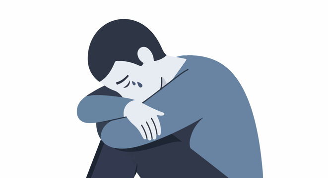 A person sits hunched over, with their arms wrapped around their knees, appearing to cry