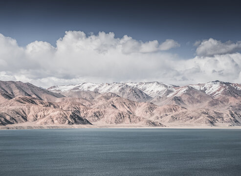 Landscape in the Pamir Mountains with a blue lake Yashilkul in the Tien Shan, a panoramic view of the highlands with snow-capped rocky peaks and the blue waters of the lake