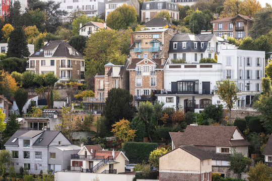 Residential hillside houses in Paris France form a dense urban neighborhood, where trees surround homes and layered architecture climbs the slope.