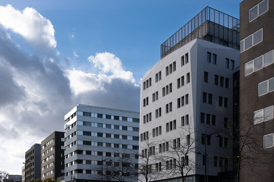 Residential apartments in Paris France show urban architecture through stacked buildings, where a white facade cuts into cloudy sky with clean shadow.