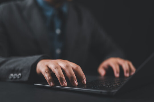 Businessperson using laptop computer at office desk, close-up of hands on keyboard, representing modern business technology, digital work, and professional productivity.