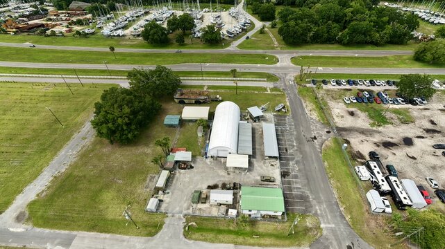 Aerial view of the Military Museum of North Florida with a white arched hangar, vintage vehicles, and green fields in Green Cove Springs, Florida, United States.