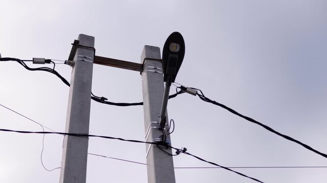 Streetlight mounted on concrete utility poles with visible electrical wires and cloudy sky background, showcasing gradual perspective change across three frames