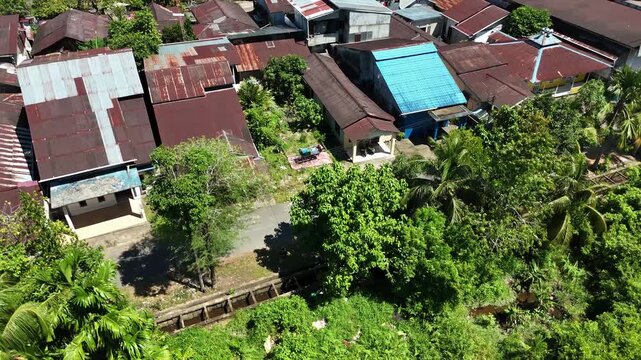 A view from above the rooftops and narrow streets of a tropical village surrounded by lush greenery in West Borneo, Indonesia.