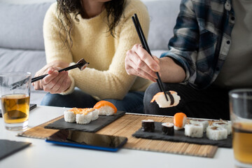 Couple eating sushi together at home with chopsticks © chandlervid85