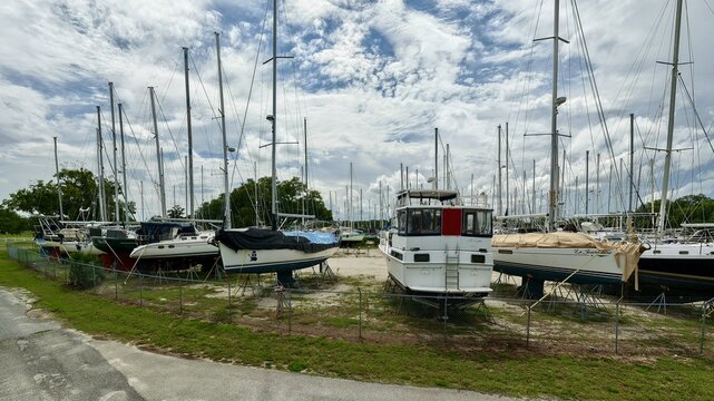 Aerial view of sailboats and motorboats stored on jack stands in a dry dock facility under a cloudy sky in Green Cove Springs, Florida, United States.
