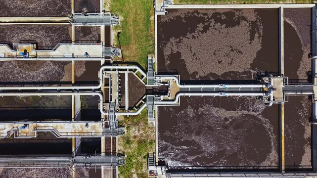 Closeup aeration basins with bubbling surfaces and turbulent mixing, visible microbial floc formation, aerator devices creating oxygenation and foam patterns,