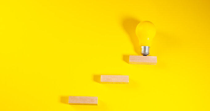Light bulb and wooden blocks on a yellow background. Creative idea concept.