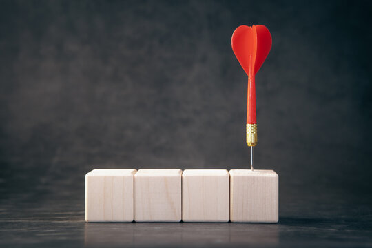 Red dart arrow on wooden cubes. Concept of leadership and success.