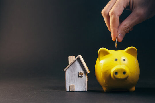 Piggy bank with a house on a dark background. The concept of saving money for the future.