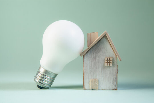 Light bulb and house model on green background, Energy saving concept.
