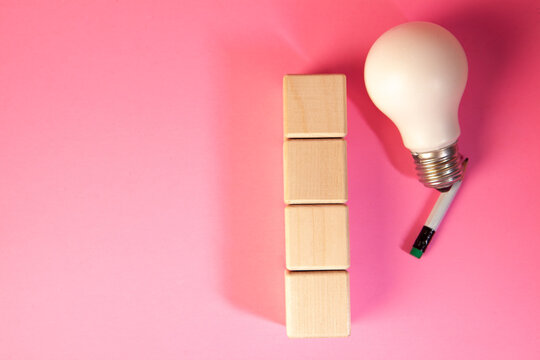 Light bulb and wooden blocks on a pink background. Business concept.