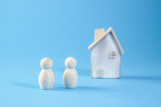 Mortgage concept. Wooden figures of people and a house on a blue background